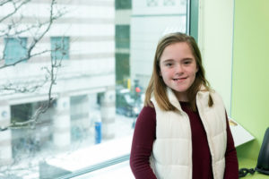 emma stands at a window durong a checkup for her laryngeal cleft