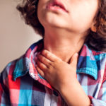 child with motility disorder holding her throat