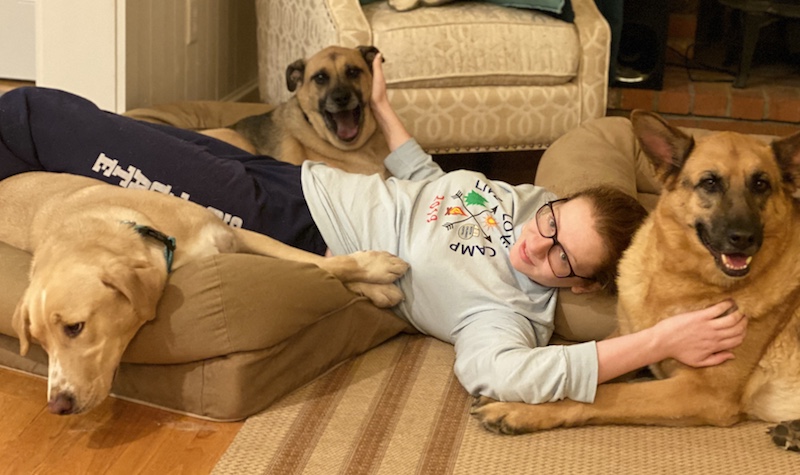 Ava, who has ACM, lies on the floor  with her three dogs