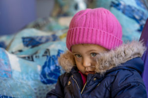 Scarlette, who has PK deficiency, poses outside in a bright pink hat