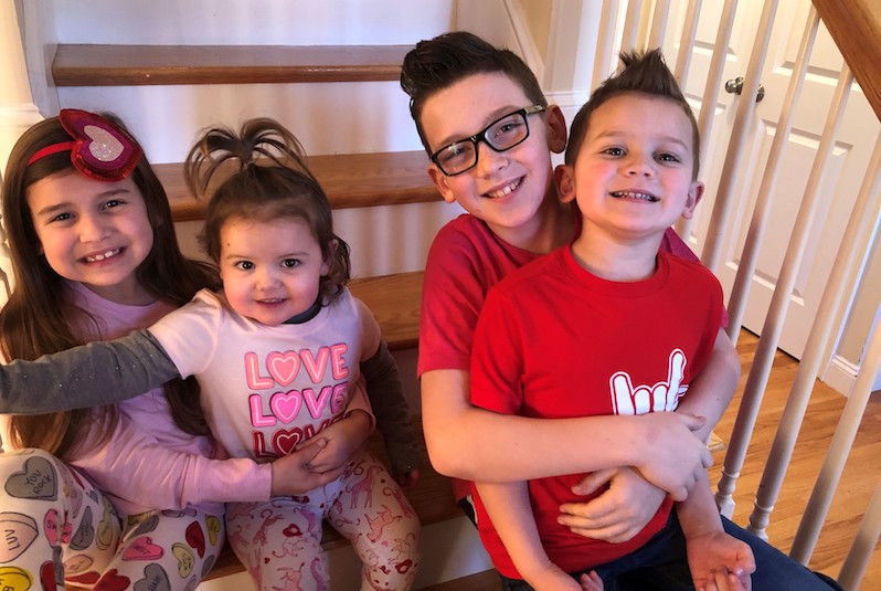 Evan, who had surgery for a papilloma, poses with his three siblings on the stairs of their home