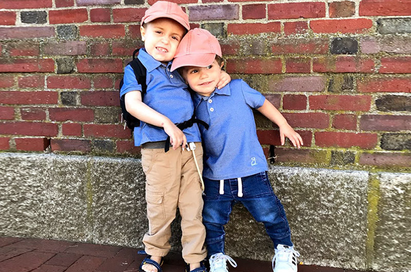 William, who has Pearson syndrome, hugs his brother as they stand against a brick wall