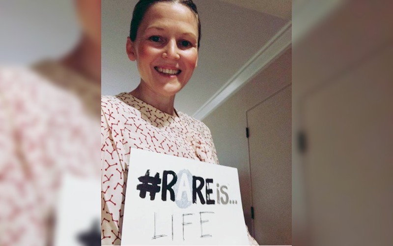 A mom who is fighting for more research for SDS, holds a sign that says "Rare is Life."