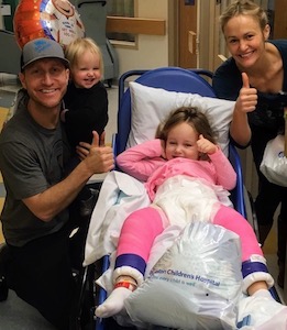 Wilkinson family at the hospital. Emma is in a wheelchair with a pink spica cast covering both legs. 