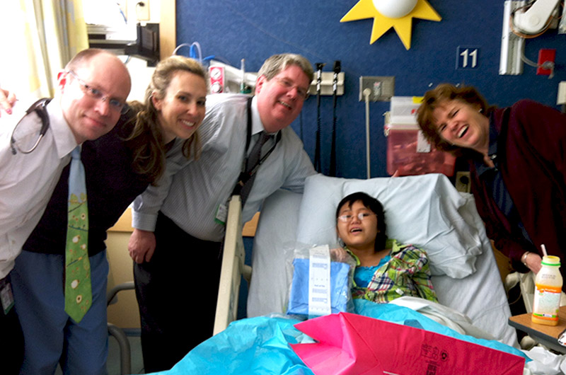 Anna, who had a rare type of brain cancer, in her hospital bed, surrounded by her care team
