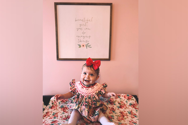 OEIS patient Aubree poses in a flowered dress.