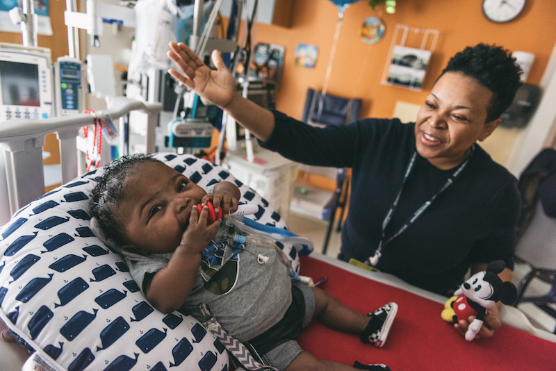 Kenny, a preemie in the ICU, smiles as his mom plays with him