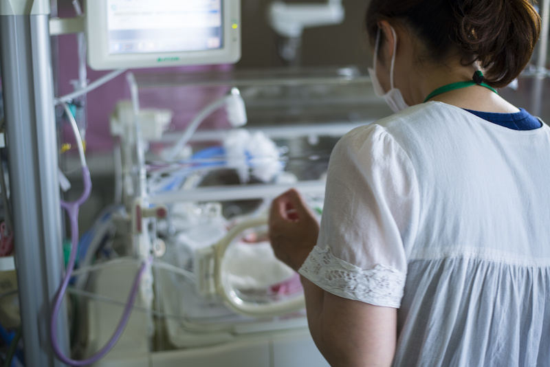 a mom approaches her baby's bed in the NICU