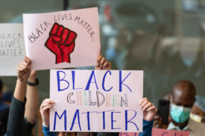Signs at a rally say "black lives matter" and "black children matter."