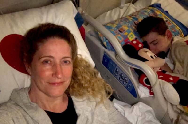 Jared asleep in a hospital bed with his mom on a cot next to him after his spinal fusion surgery during the COVID-19 outbreak. 