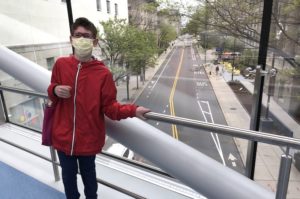 Jared, who has scoliosis, in a red jacket on the Boston Children's skybridge overlooking an empty street.