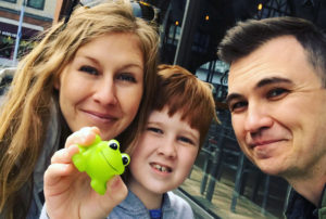 Megan, Henry, and Dr. Grant Hogue pose for a picture. Henry holds up a green frog toy.