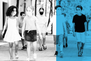 kids walking down a sidewalk all wearing masks