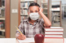 Boy sitting at desk in school wearing mask during COVID-19 outbreak