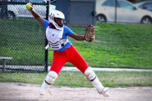 Gwen, who has asthma, in catcher's protective gear, winds up to throw a ball.