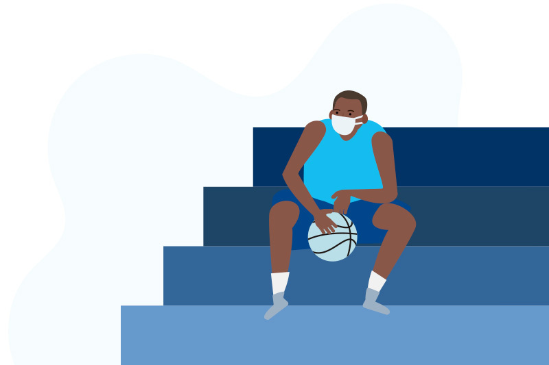 A basketball player sits alone in bleachers that are empty due to COVID-19.