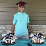 maythum, who had midaortic syndrome, at his college graduation. he has two cakes and is wearing a blue shirt