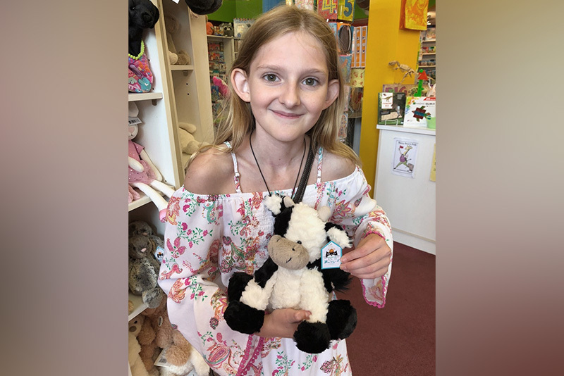 Adella holds a stuffed animal and smiles after treatment for thyroid cancer.