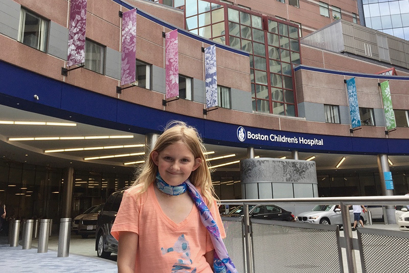 Adella poses outside Boston Children's, where she is treated for thyroid cancer.