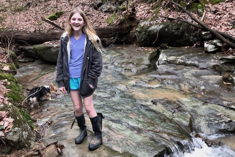 adella stands near a waterfall after recovering from thyroid cancer
