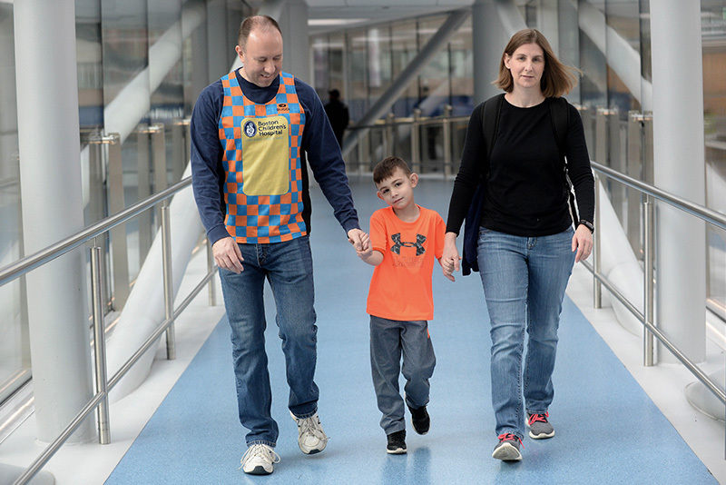 James, who had a stroke, walks in between his parents while holding their hands.