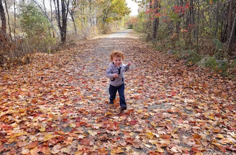 Finn, who was born with clubfoot, runs down a leafy path.