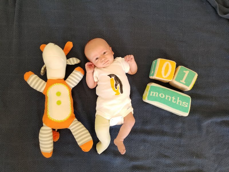 Finn, who was born with clubfoot, next to a doll that is the same age as him and blocks that say 1 month