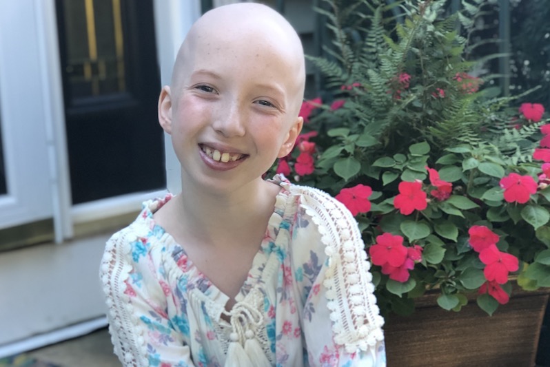 Carly, who was treated for Wilms tumor, sits on her front porch. 