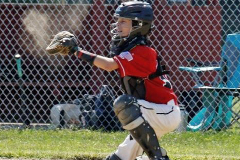 an action shot of brendan, who had bladder diverticula, acting as his baseball team's catcher