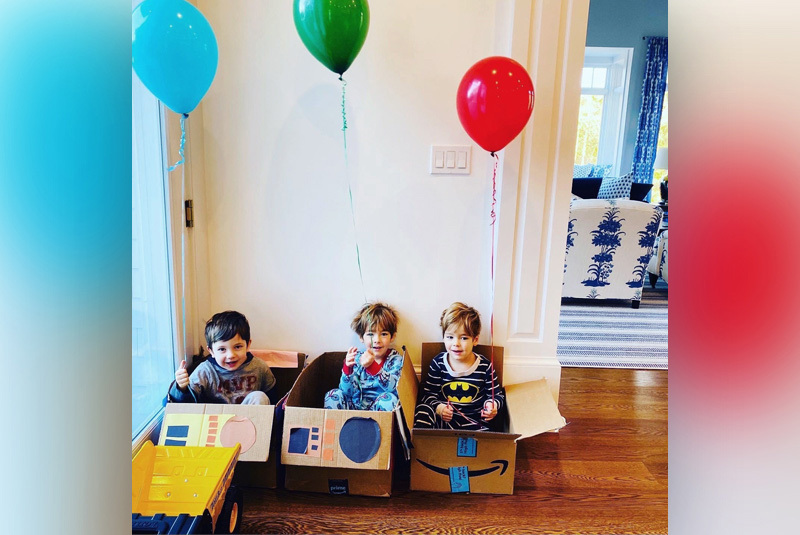Evan, West, and James sit in boxes while holding balloons. Evan and West both had cardiac surgery. 
