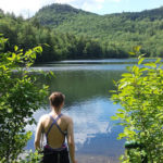 lucie, who has chronic pain, stands looking at a lake