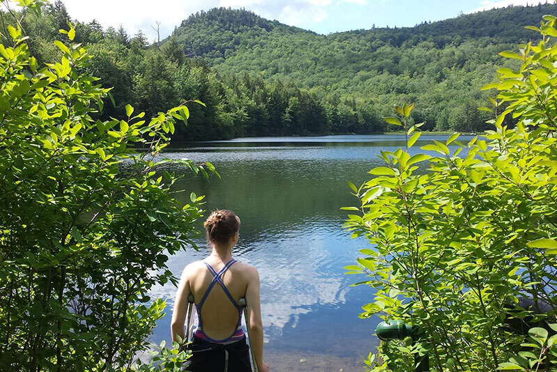 lucie, who has chronic pain, stands looking at a lake