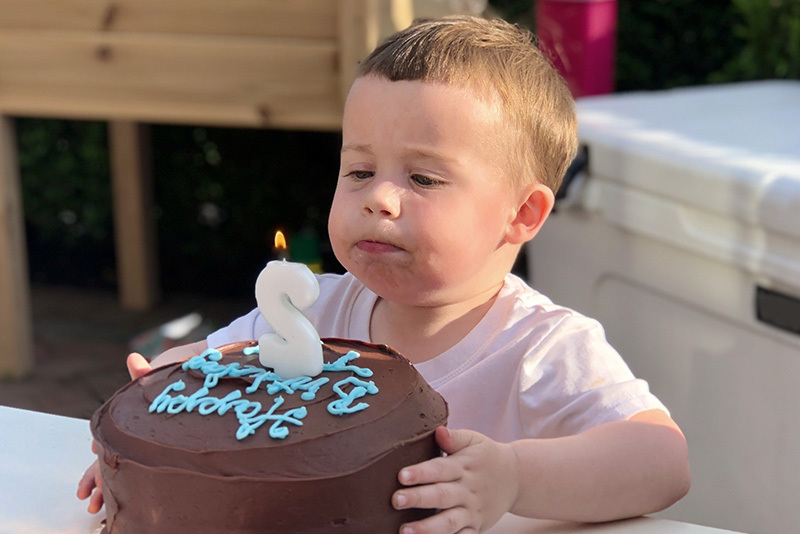 tyler blows out a candle on his birthday cake after treatment for a laryngeal cleft