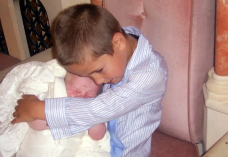 Marc, who was born with ALD, holds his baby brother, Matthew, in a blanket.