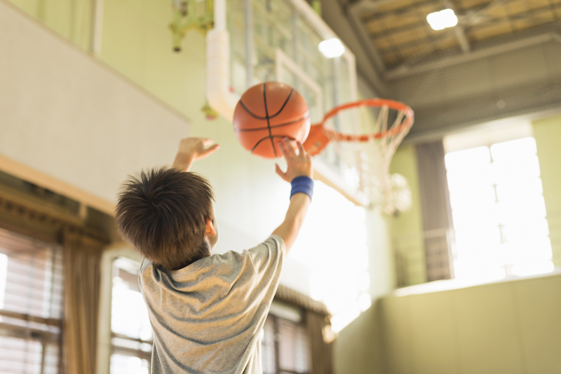 young boy shooting basketball into hoop