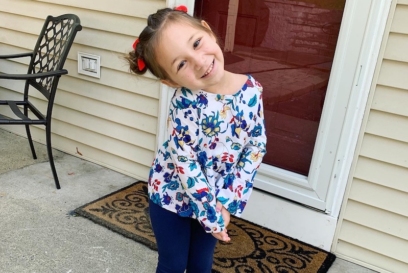 Charlee, who had neuroblastoma, poses in front of a door.