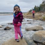 Caroline, who was treated for pulmonary vein stenosis, standing on rocks at a lake
