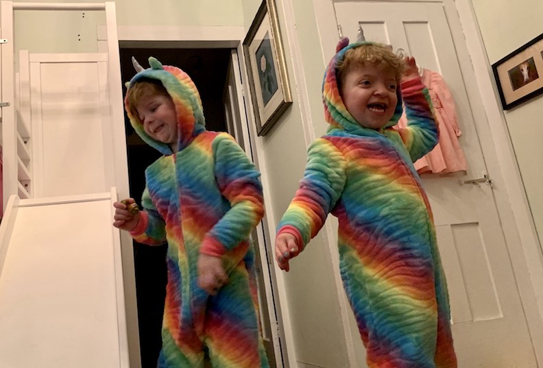 Maise, who has Apert syndrome, dances with her sister in matching rainbow unicorn costumes.
