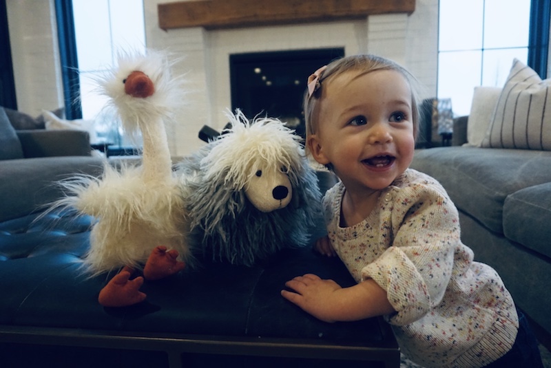 Charleston, who had heart surgery, poses with two stuffed animals at her home