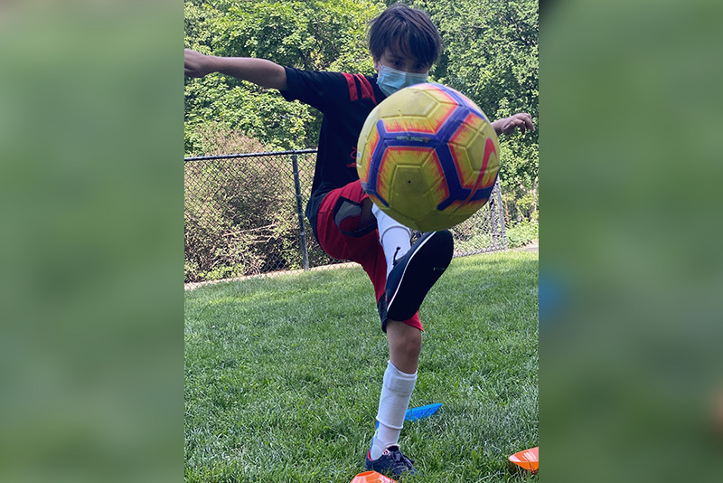 cooper, who has. cerebral palsy, kicks a soccer ball.