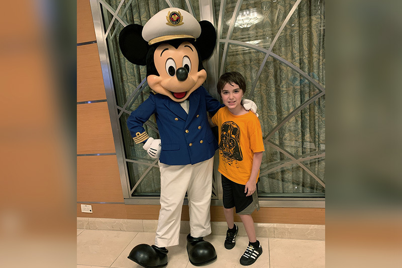 Cooper, who has cerebral palsy, poses with Mickey Mouse.