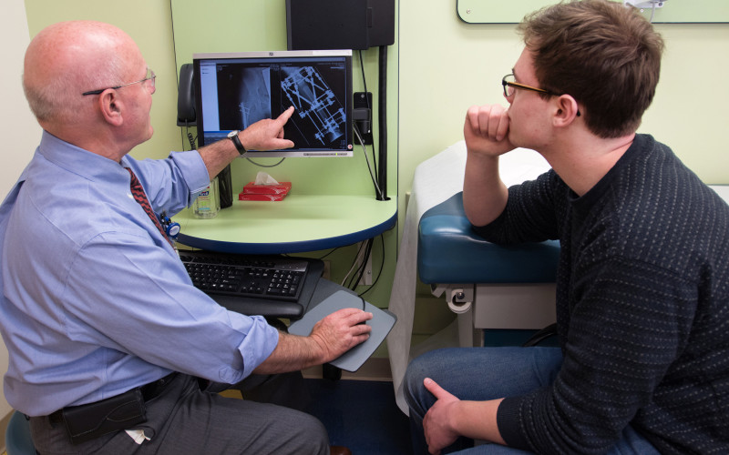 Dr. Kasser and George look at an x-ray image of his leg with an external fixator holding it in place during a lengthening procedure. 