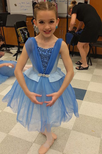 Teagan, who was diagnosed with Perthes disease, prepares for a performance in a blue dance costume.