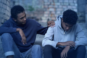 Two sitting teens, one comforting the other