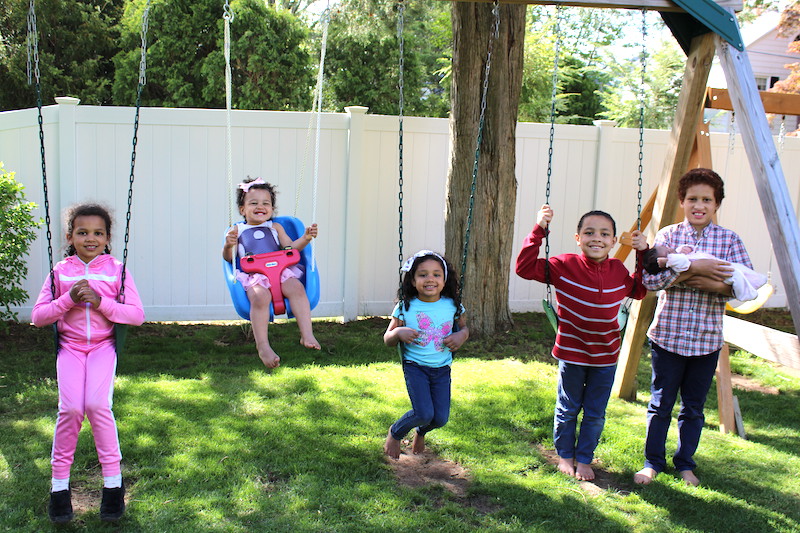 Jeanne, who has infantile scoliosis, plays on the swings with her brothers and sisters. She is wearing her second brace. 