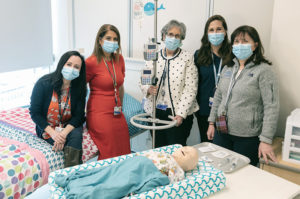 Group of nurses from the HPN Program standing over a hospital bed