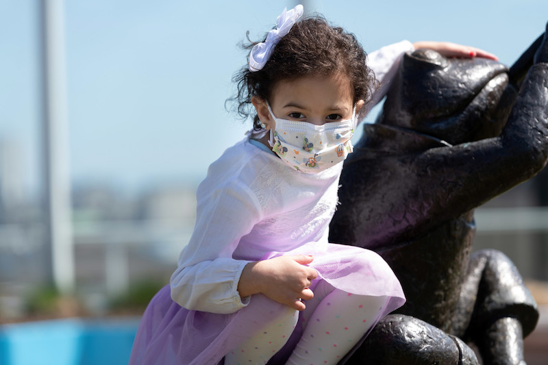 Laila, who has trichohepatoenteric syndrome, poses by a sculpture on the boston children's roof garden
