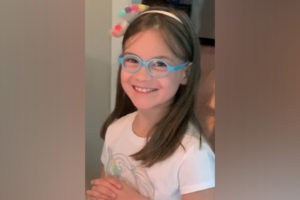 scarlet, who had sdr surgery, smiles at the camer. she is wearing blue glasses