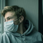 teen boy wearing a mask to suggest he has post-covid symptoms