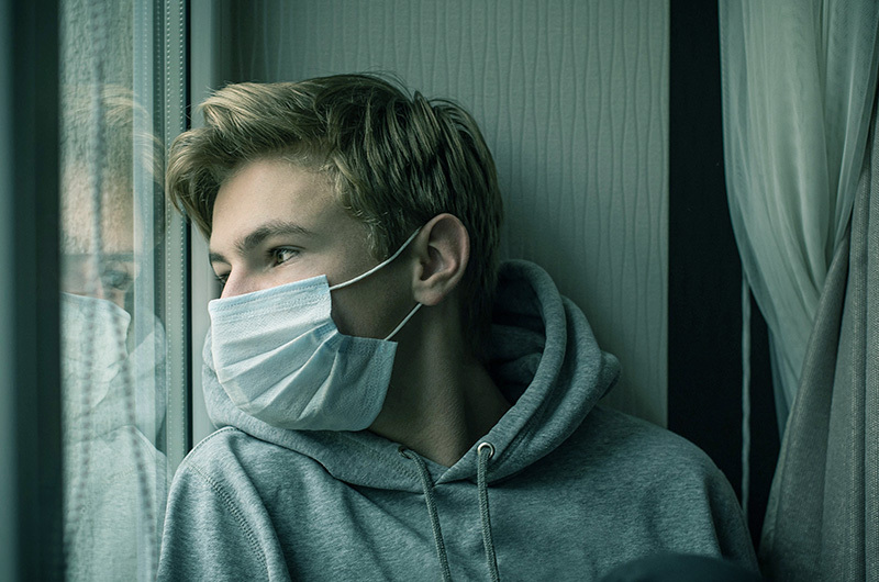 teen boy wearing a mask to suggest he has post-covid symptoms